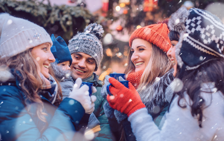 eine Gruppe von Freunden trinkt in der Kälte Glühwein auf einem Weihnachtsmarkt - © Kzenon - stock.adobe.com