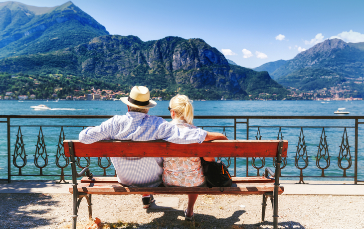 Comer See,Dorf Bellagio,Italien. Älterer Paarwochenendenausflug, der Rest auf der Bank durch großartigen See Como in Italien hat. Sonniger Tag Landschaft. Touristen, die Ansicht über populäre Touristenattraktion bewundern. - ©Feel good studio - stock.adobe.com